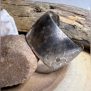 Silver cuff bracelet with antiqued spiral design.